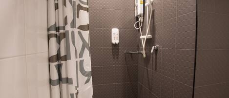 A shower area with a tiled wall, a showerhead, and a control panel.