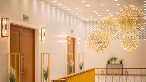A modern hotel lobby with a wooden door, a yellow railing, and decorative spherical light fixtures. - Socool Grand Hotel (Nang Rong)