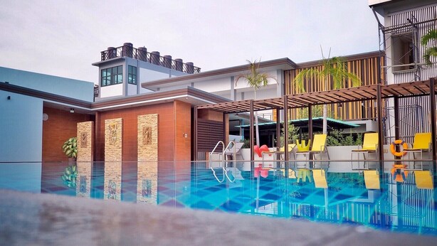 A modern hotel with a swimming pool, outdoor seating, and a mix of contemporary and traditional architecture. - Socool Grand Hotel (Nang Rong)