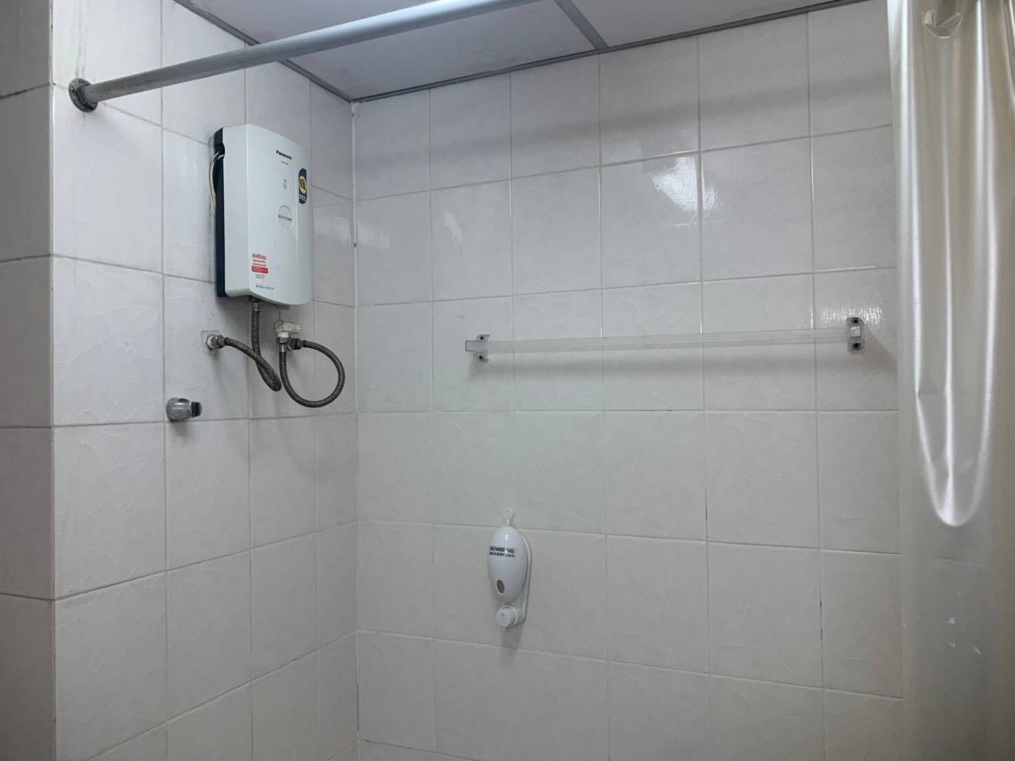 Zona de ducha con calentador de agua, secamanos y perchero para toallas.