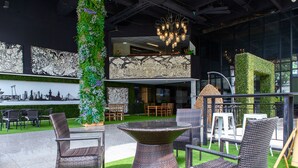 Un espace extérieur aménagé avec des meubles en osier, une table ronde et une colonne décorative.