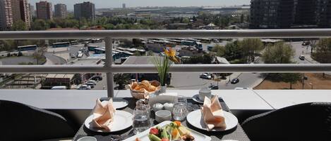 Una mesa servida con desayuno, con vistas a un paisaje urbano con edificios y una carretera.