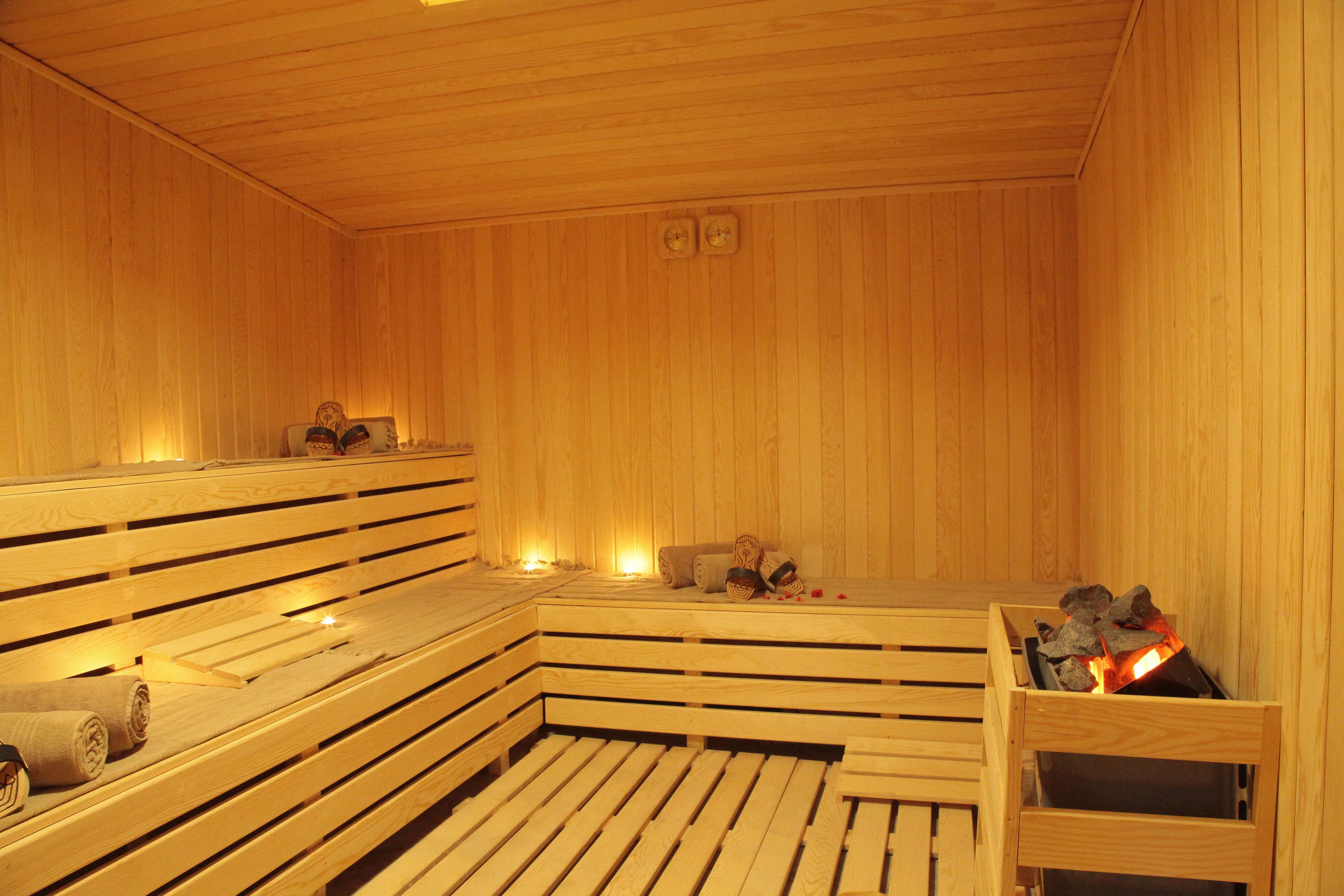 Un sauna en bois, doté de bancs et d’un foyer central.