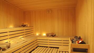 Un sauna en bois, doté de bancs et d’un foyer central.