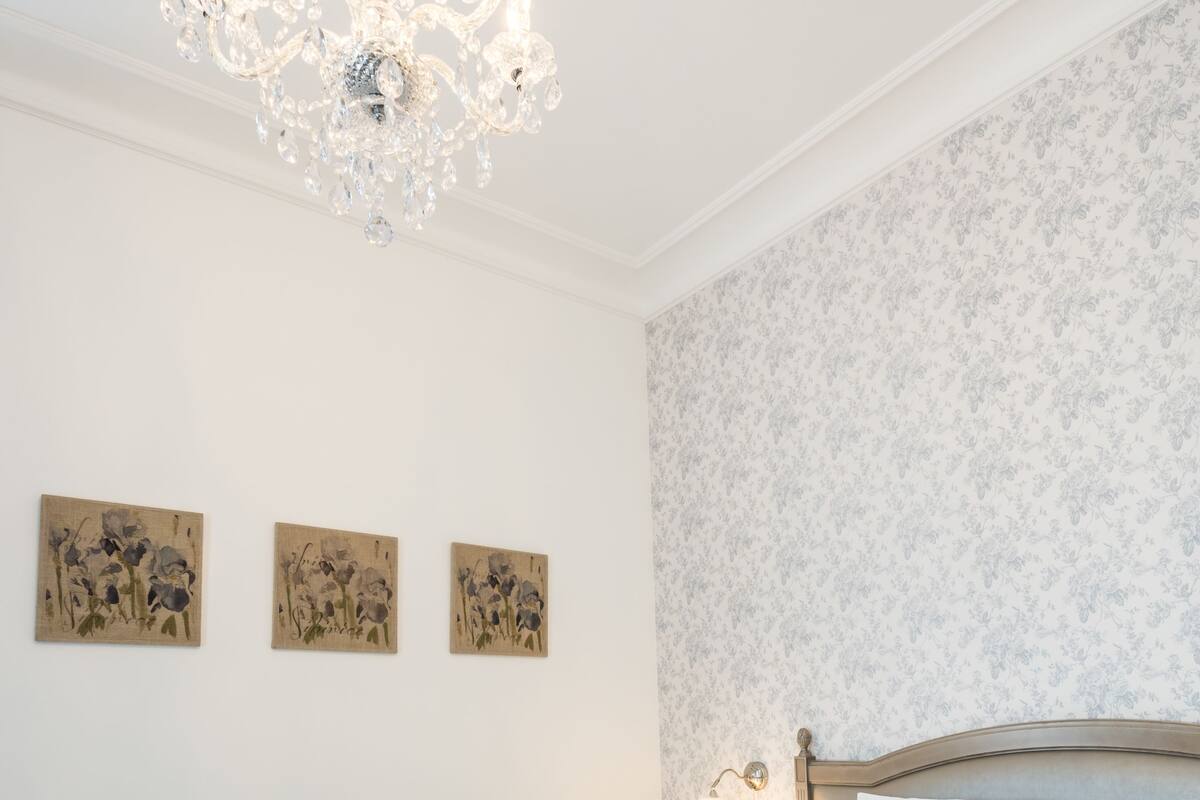 Une chambre à coucher avec un grand lit, un lustre et trois tableaux accrochés au mur.