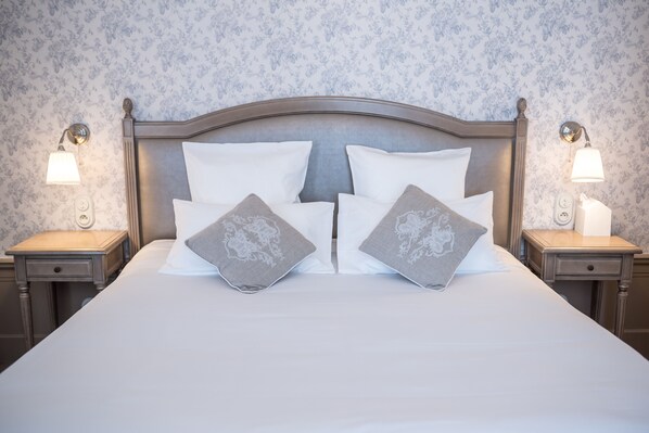 A neatly made bed with white and grey pillows, wooden headboard, and two bedside tables with lamps. - Château de Montabert (Montaulin)