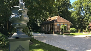 Un jardín con una urna grande y un edificio pequeño con techo de tejas.