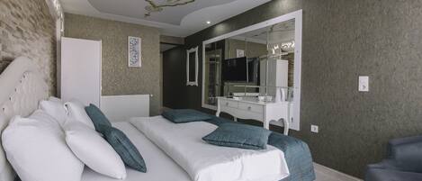 A modern bedroom with a large bed, a vanity with a mirror, and a television.
