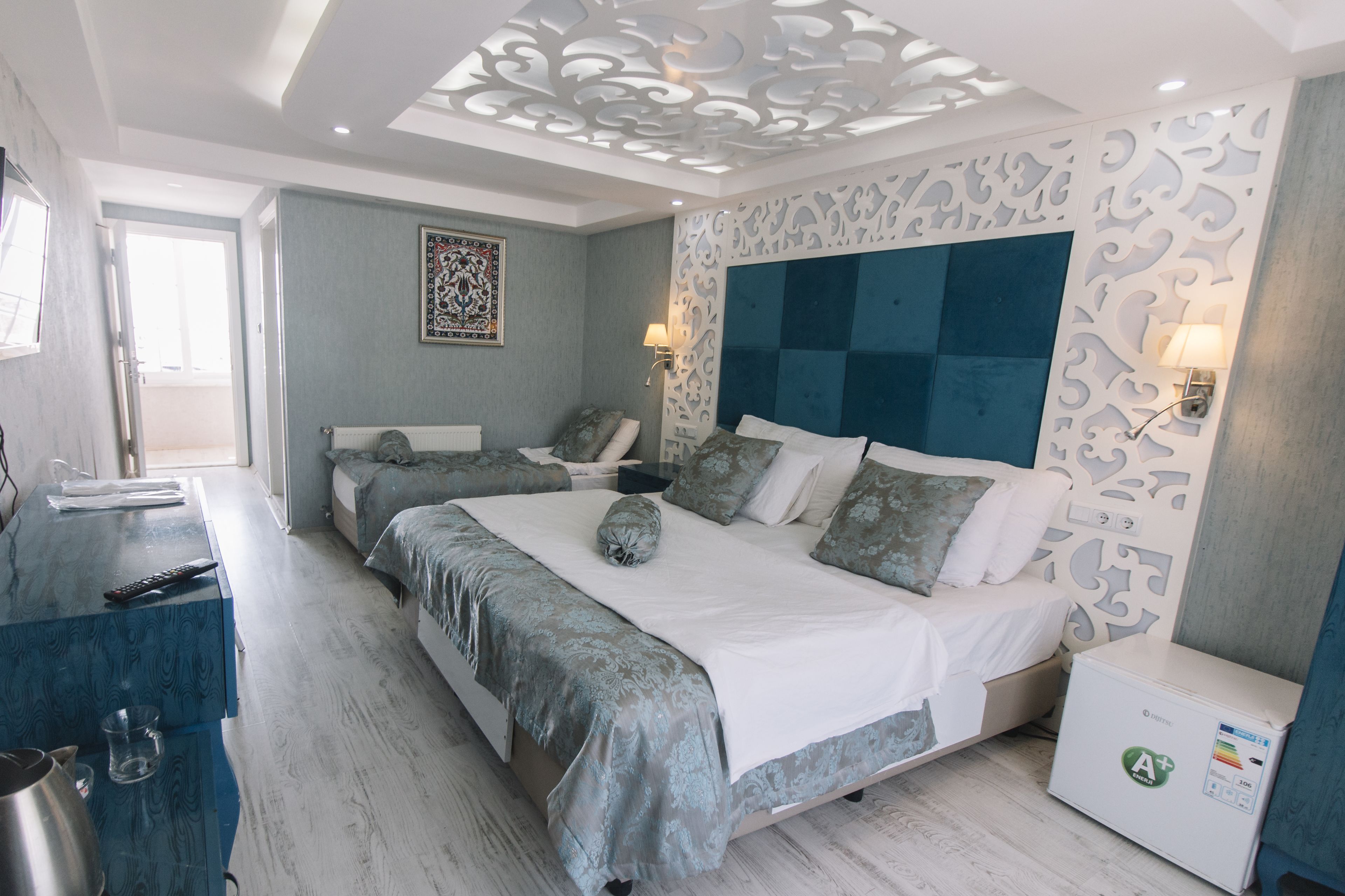 A modern bedroom with a large bed, two bedside tables, and a decorative ceiling.