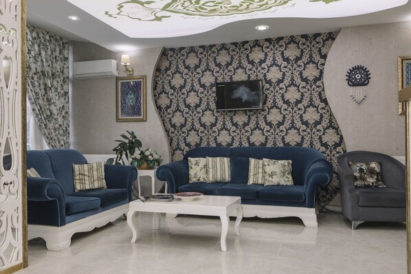 A living room with two blue sofas, a white coffee table, and a grey armchair.