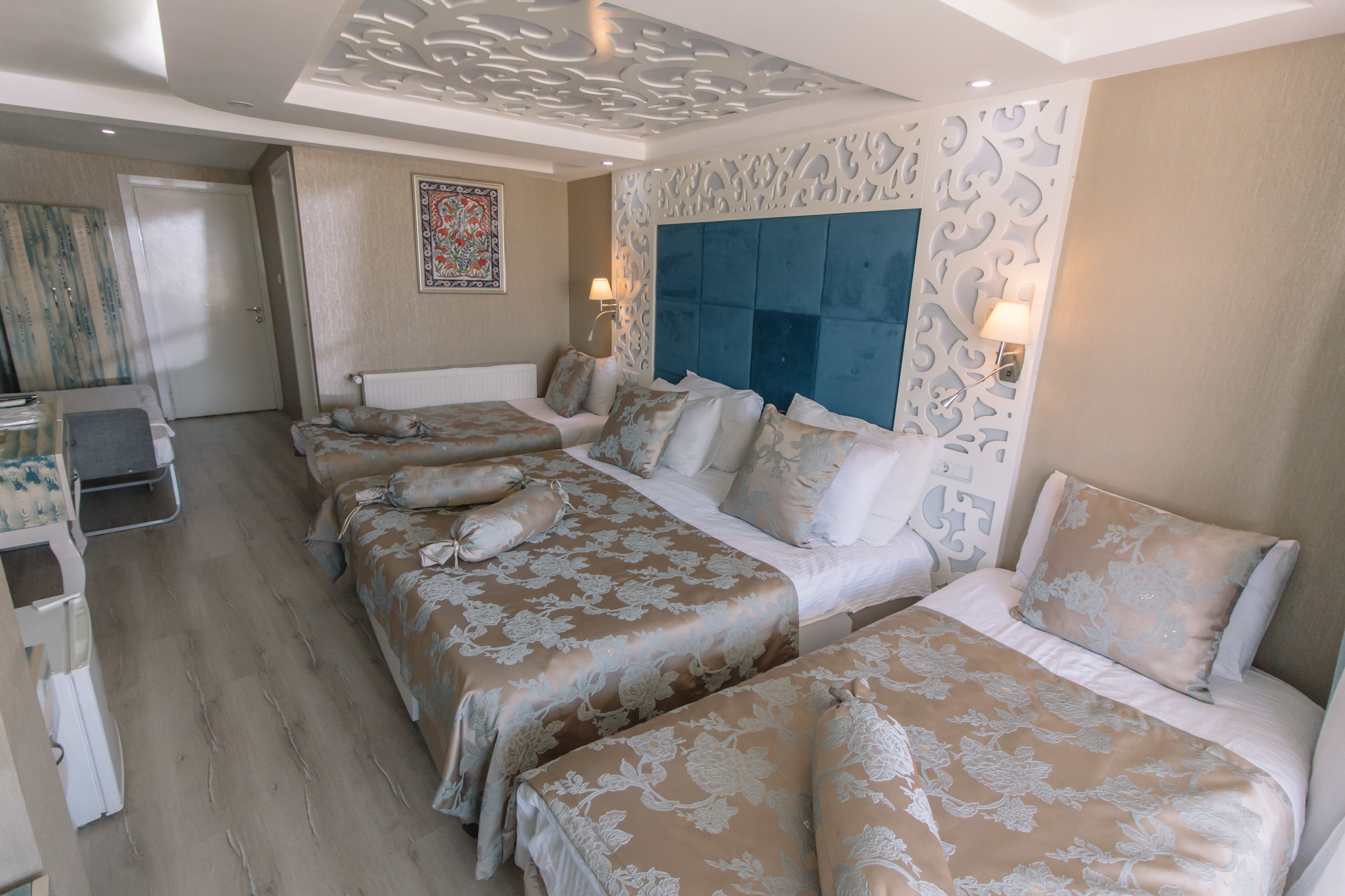 Une chambre d’hôtel avec un grand lit, deux petits lits, un bureau et une chaise.