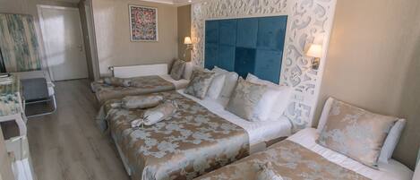 Une chambre d’hôtel avec un grand lit, deux petits lits, un bureau et une chaise.