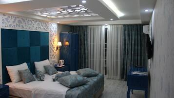 A modern bedroom with a large bed, a nightstand, a lamp, and a TV on a stand.