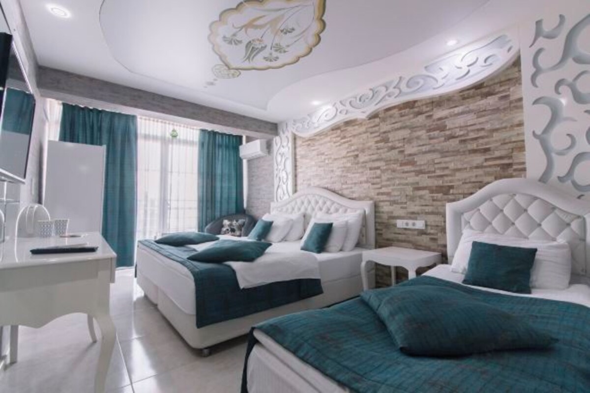 A modern hotel room with two beds, a desk, and a TV.