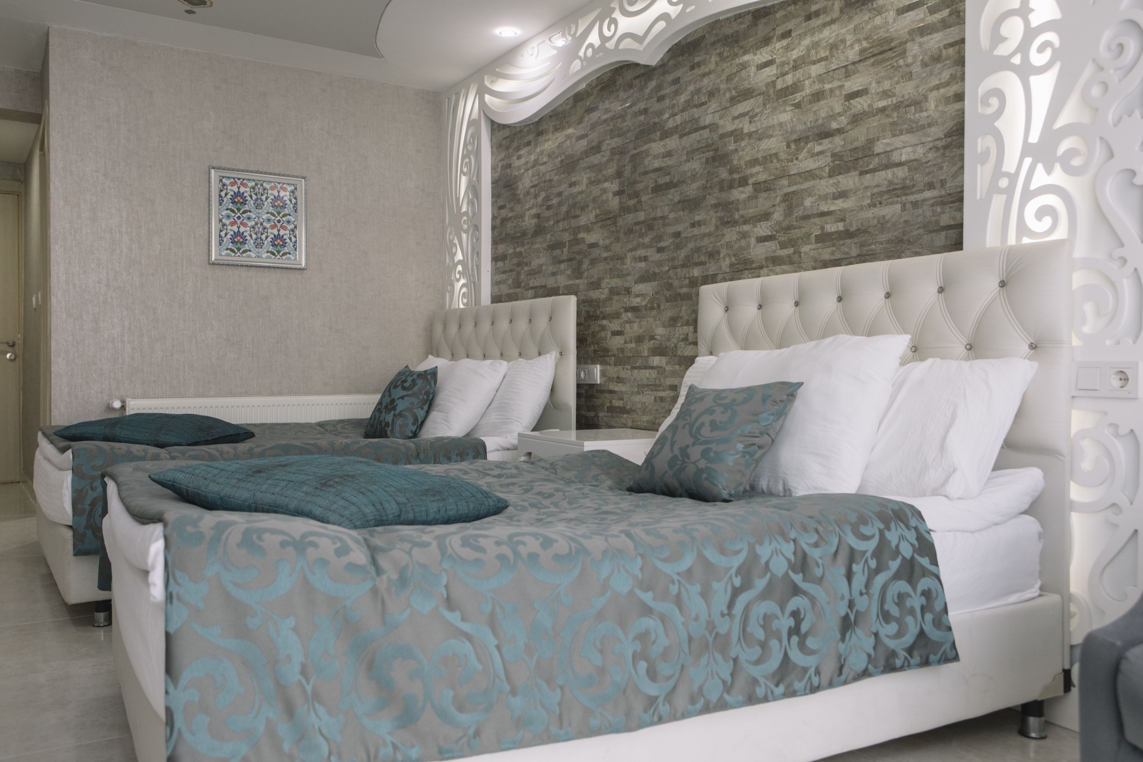A bedroom with two beds, a decorative wall, and a patterned bedspread.