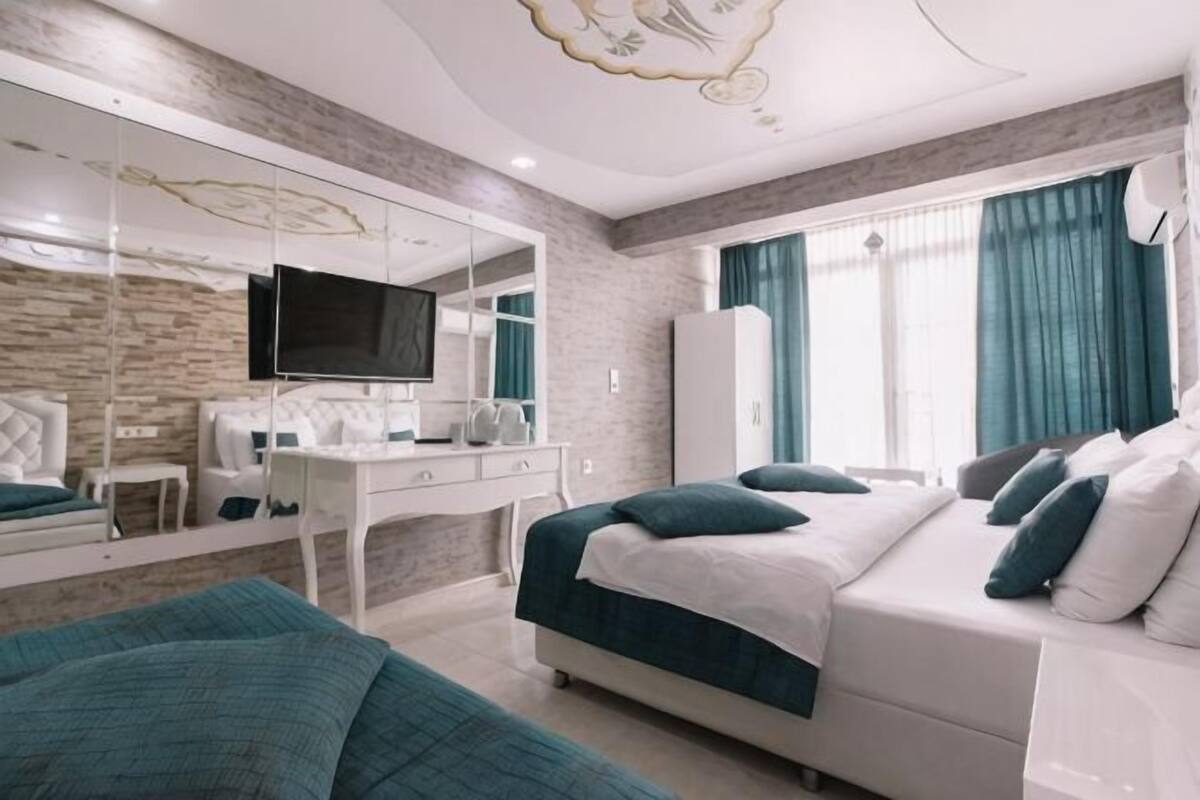 A bedroom with a bed, a desk, a TV, and a wardrobe.