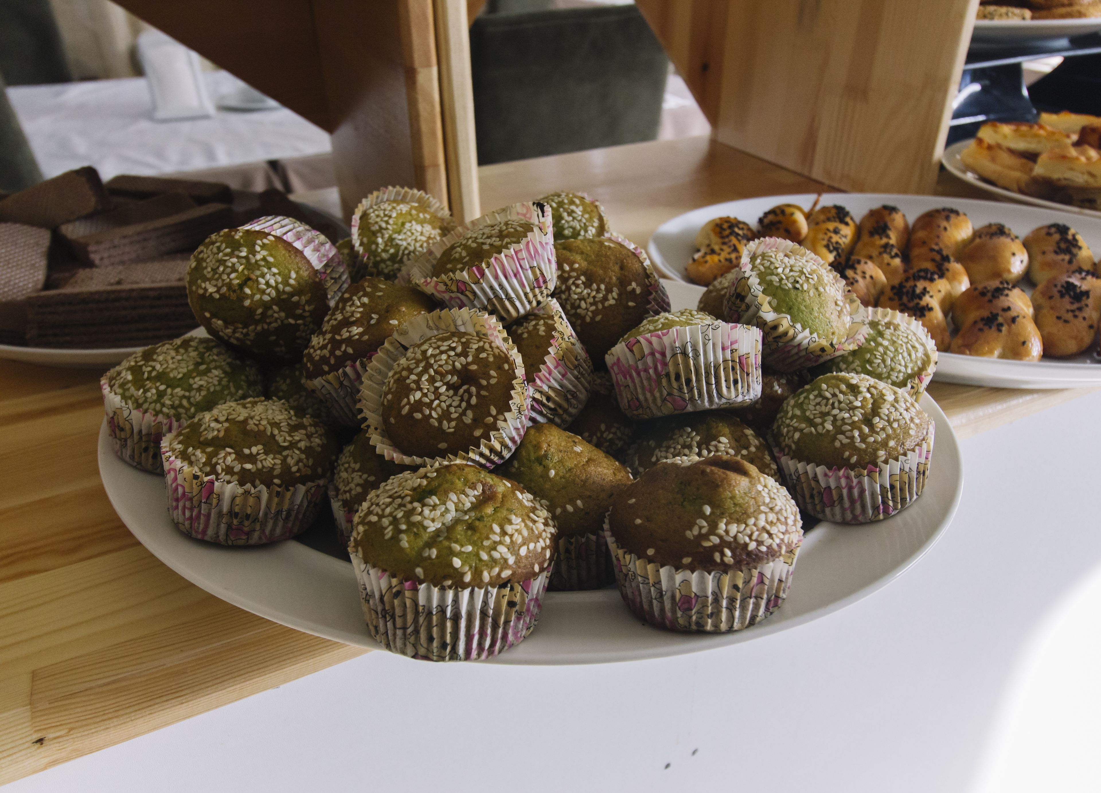 A plate of muffins with sesame seeds on a table.