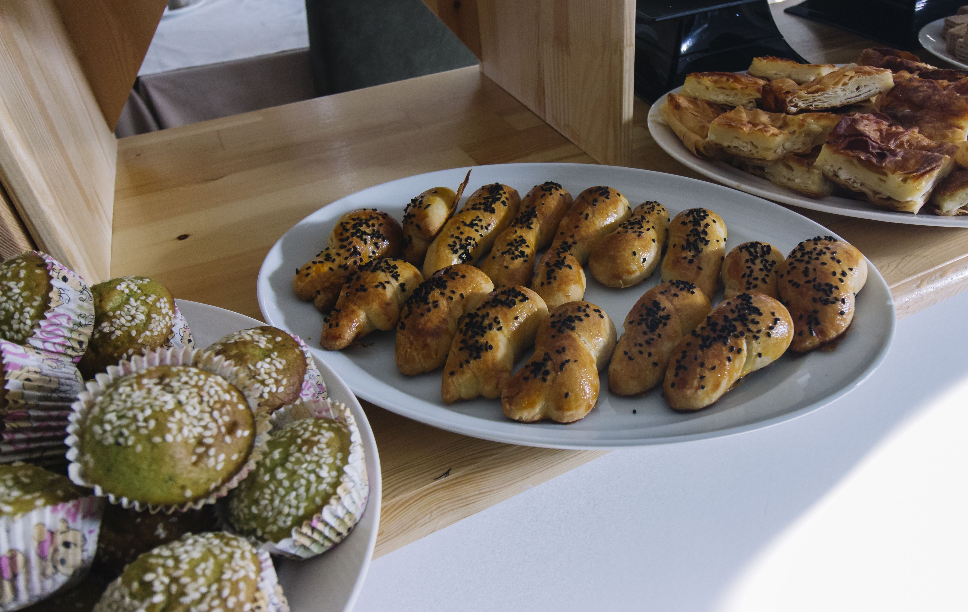 Una mesa con diversas opciones de panadería, incluyendo pan y magdalenas, dispuestas en platos.