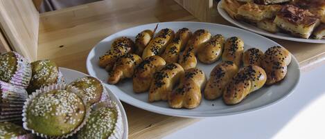 Una mesa con diversas opciones de panadería, incluyendo pan y magdalenas, dispuestas en platos.
