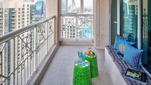 Un balcon offrant une vue sur le paysage urbain, un coin salon confortable avec des coussins et des tabourets décoratifs.