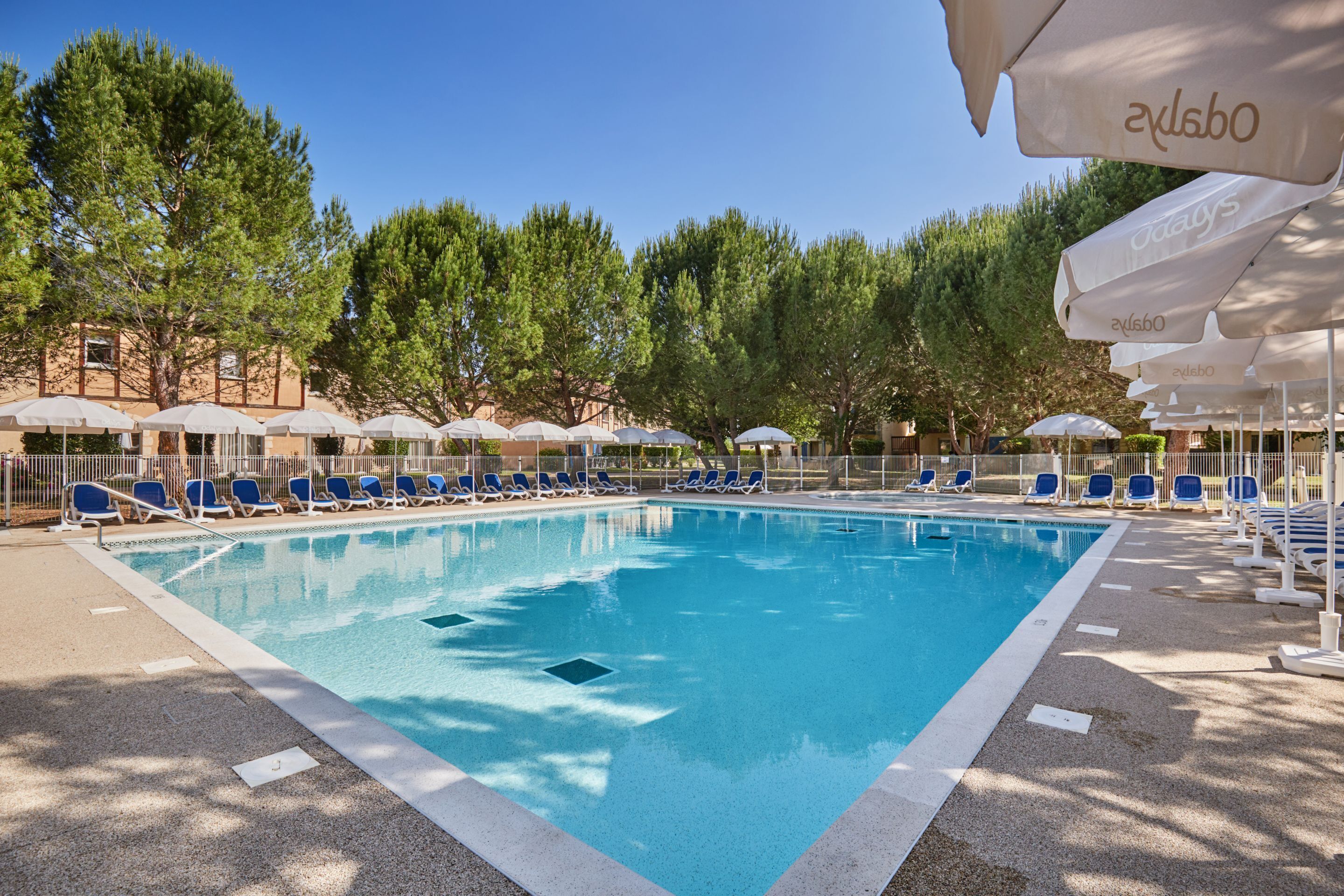 A swimming pool with blue water, surrounded by lounge chairs and umbrellas.