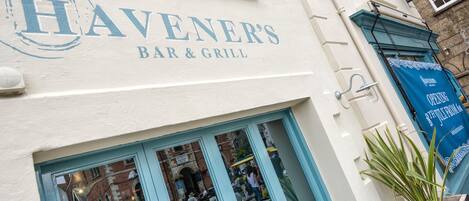 HAVENER'S BAR & GRILL, amb façana blanca i detalls blaus.