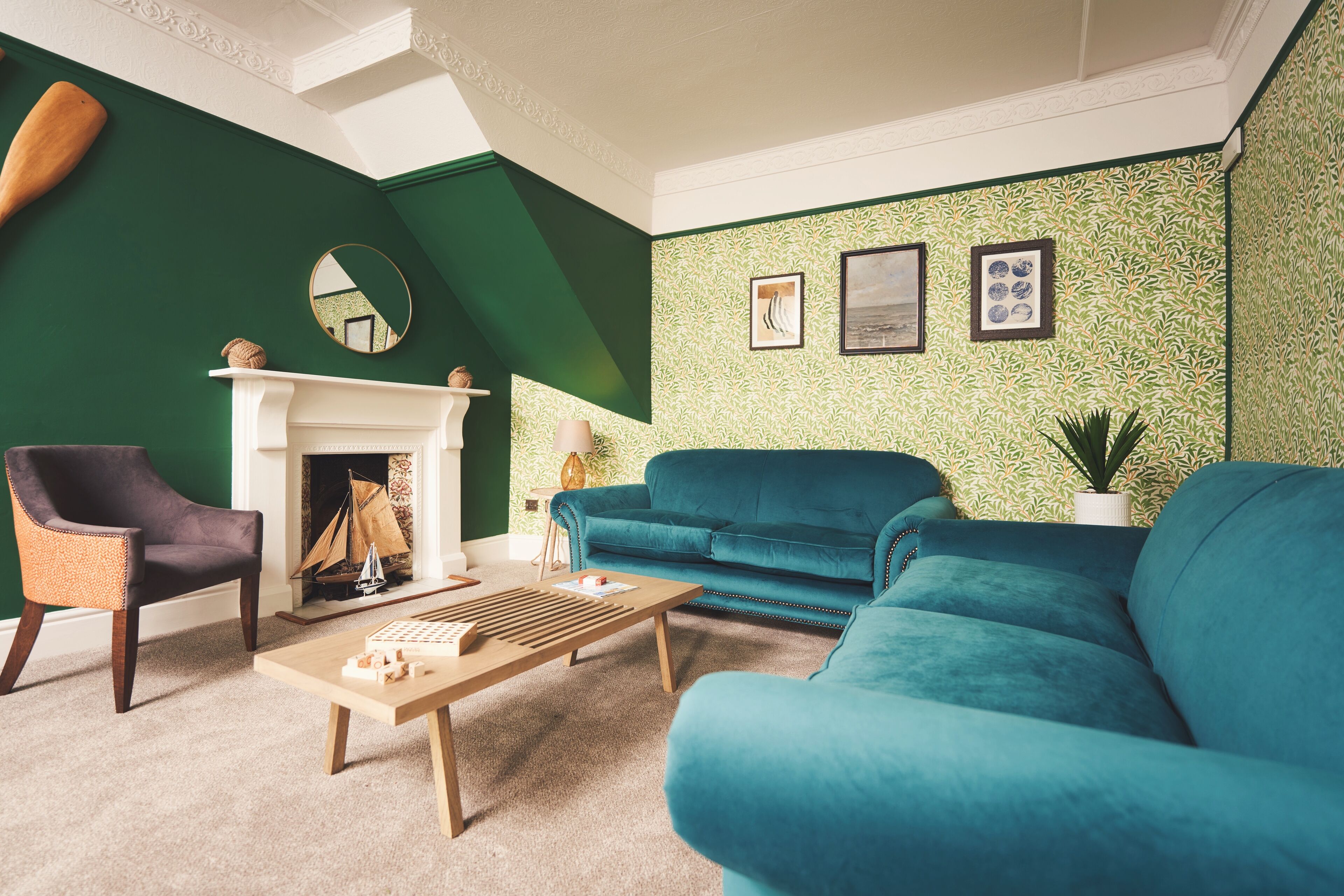 A living room with a green wall, a fireplace, a blue sofa, and a wooden coffee table.