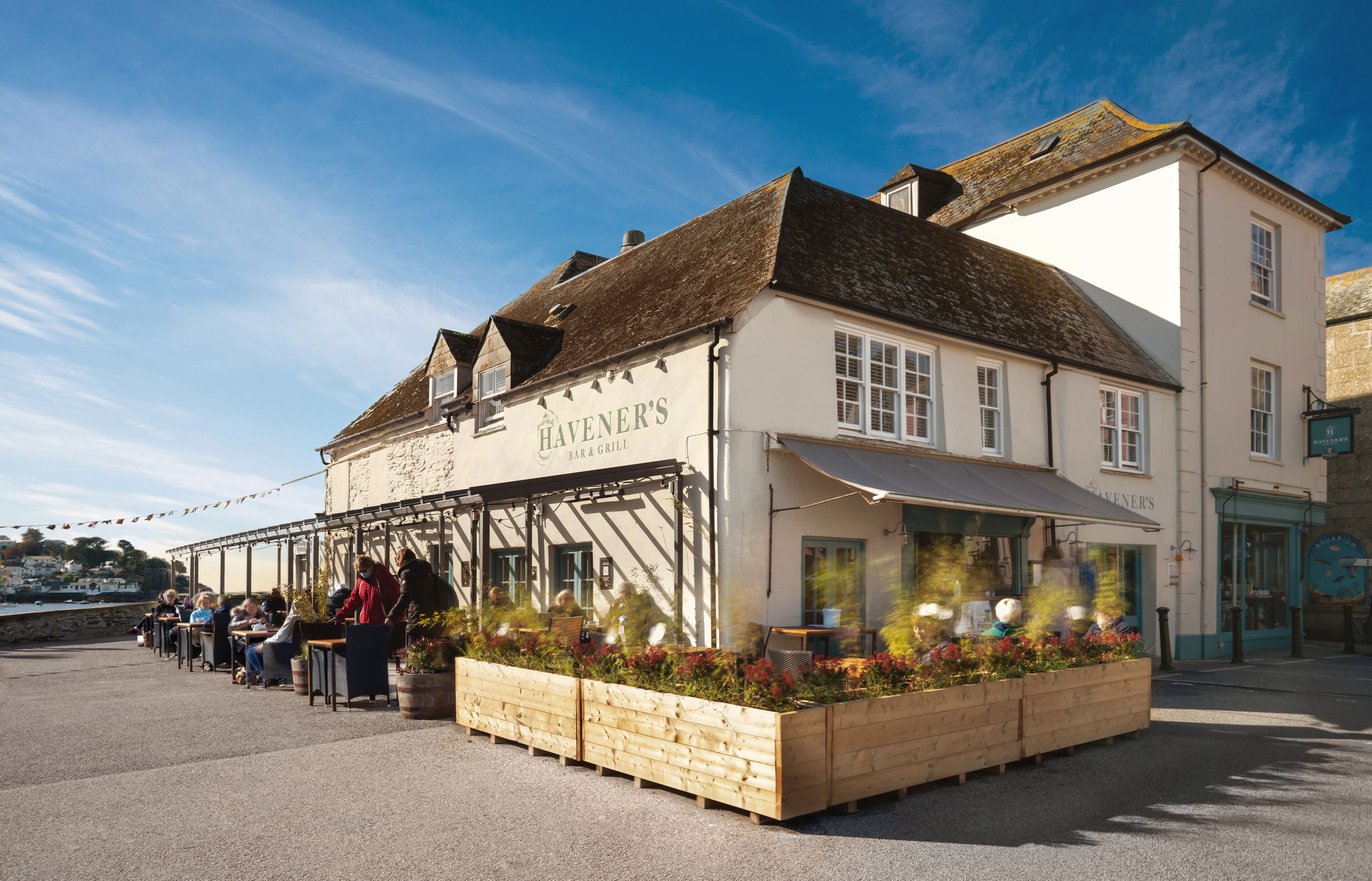 A traditional pub with outdoor seating, a terrace, and a view of the sea.