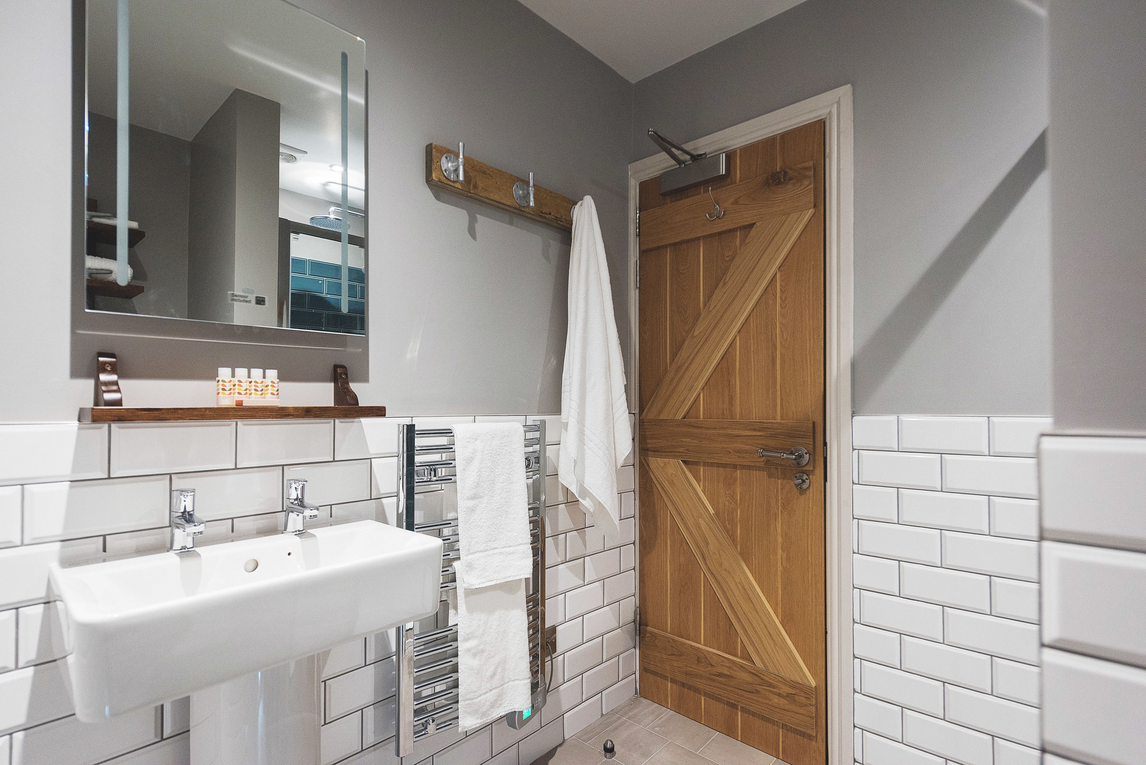 Un baño con un lavamanos blanco, un espejo y una puerta de madera.