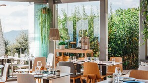 An outdoor dining area with tables and chairs, a lamp, and potted plants. - Hôtel La Villa Douce (Rayol-Canadel-sur-Mer)