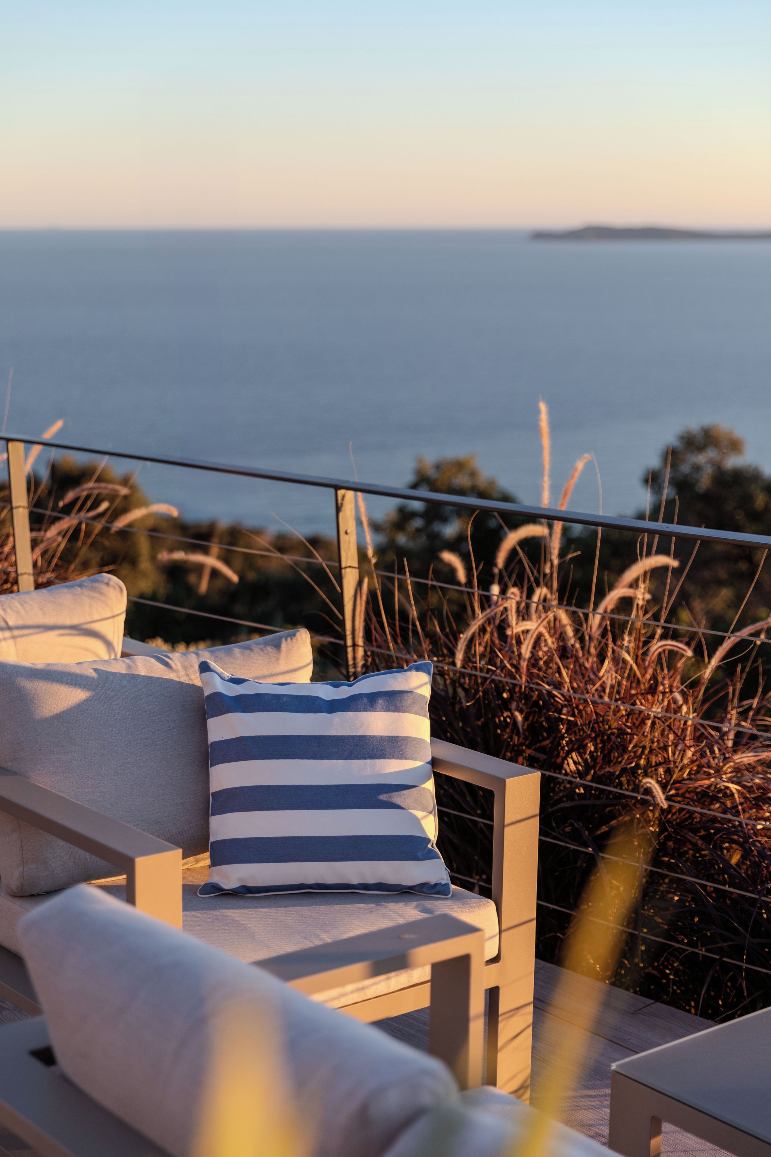 Eine Strandterrasse mit Meerblick, ausgestattet mit einer Couch und einem gestreiften Kissen.