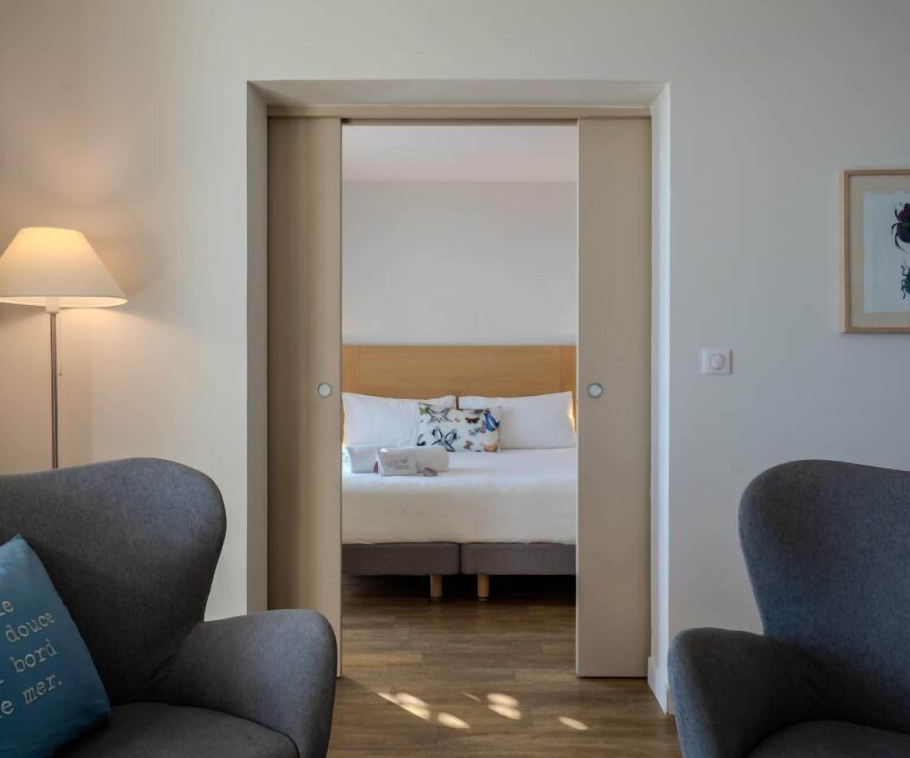 Quarto de hotel com cama, escrivaninha e cadeira.