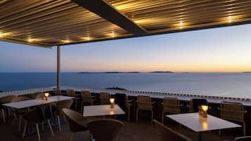 An outdoor seating area with tables and chairs, overlooking a body of water.