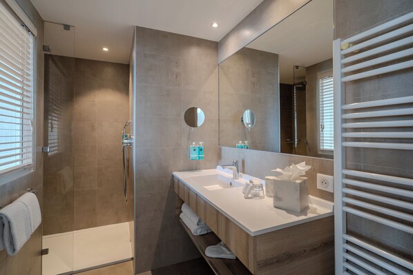 Un baño moderno con cabina de ducha, un espejo grande y un lavabo blanco.