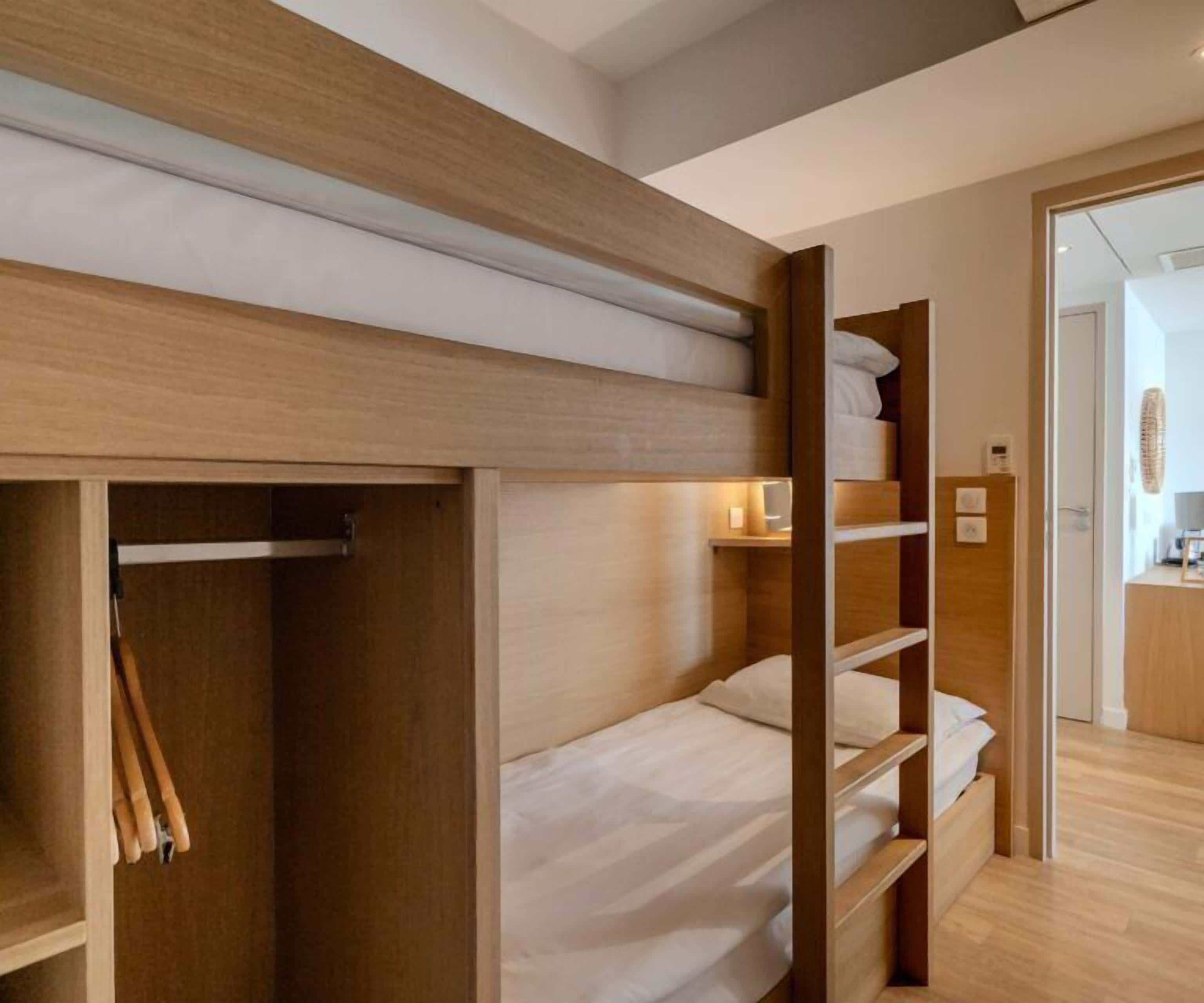 A bunk bed room with wooden walls and a wooden floor.