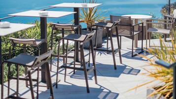 Een terras met tafels en stoelen met uitzicht op een waterpartij.