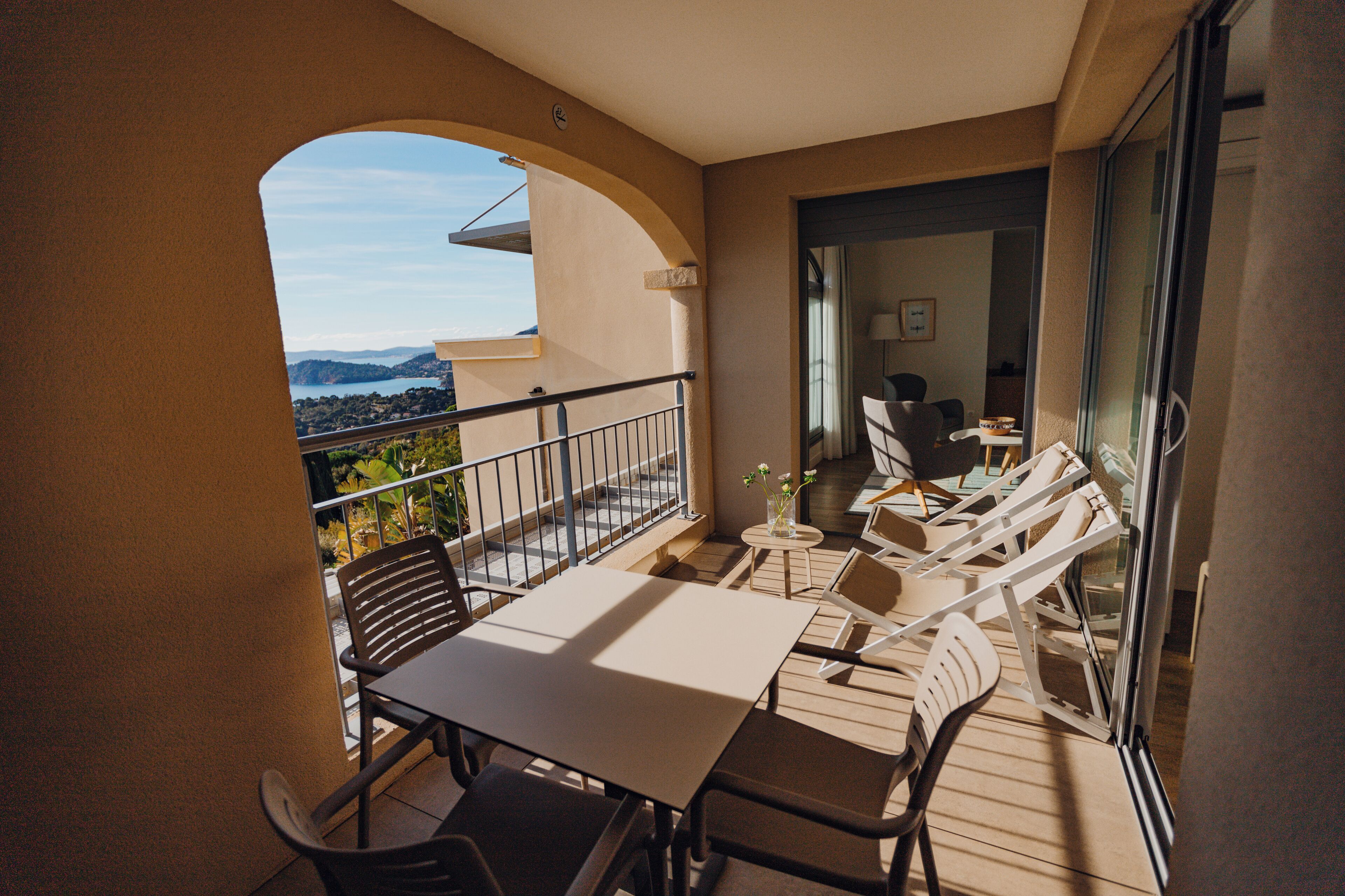 Un balcon avec une table et des chaises, une vue sur la mer et un coin repas avec des chaises et une table.