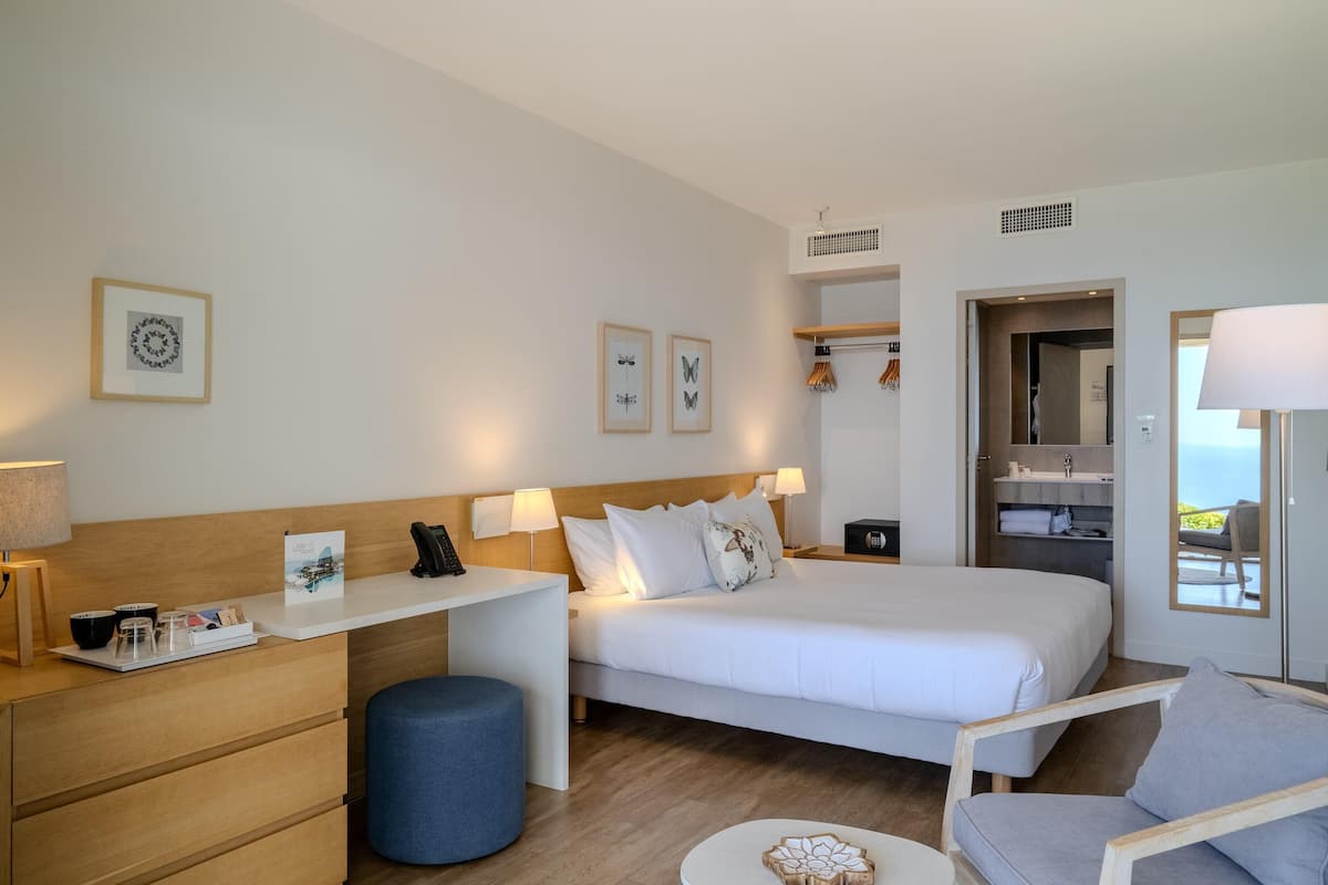 A modern hotel room with a bed, desk, and seating area.