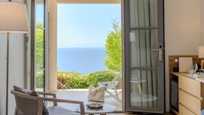 A room with a view of the sea, a sliding glass door, a dining area, and a small table with a chair. - Hôtel La Villa Douce (Rayol-Canadel-sur-Mer)