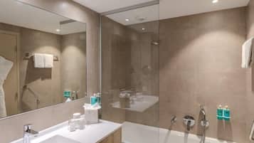 A modern bathroom with a glass-enclosed shower, a double sink vanity, and a large mirror.