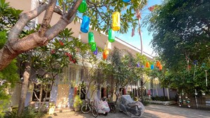 A paved courtyard with a covered motorcycle, bicycles, and potted plants. - Clover Homestay (Probolinggo)