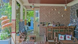 An indoor dining area with wooden tables and chairs, a brick wall, and hanging lights.