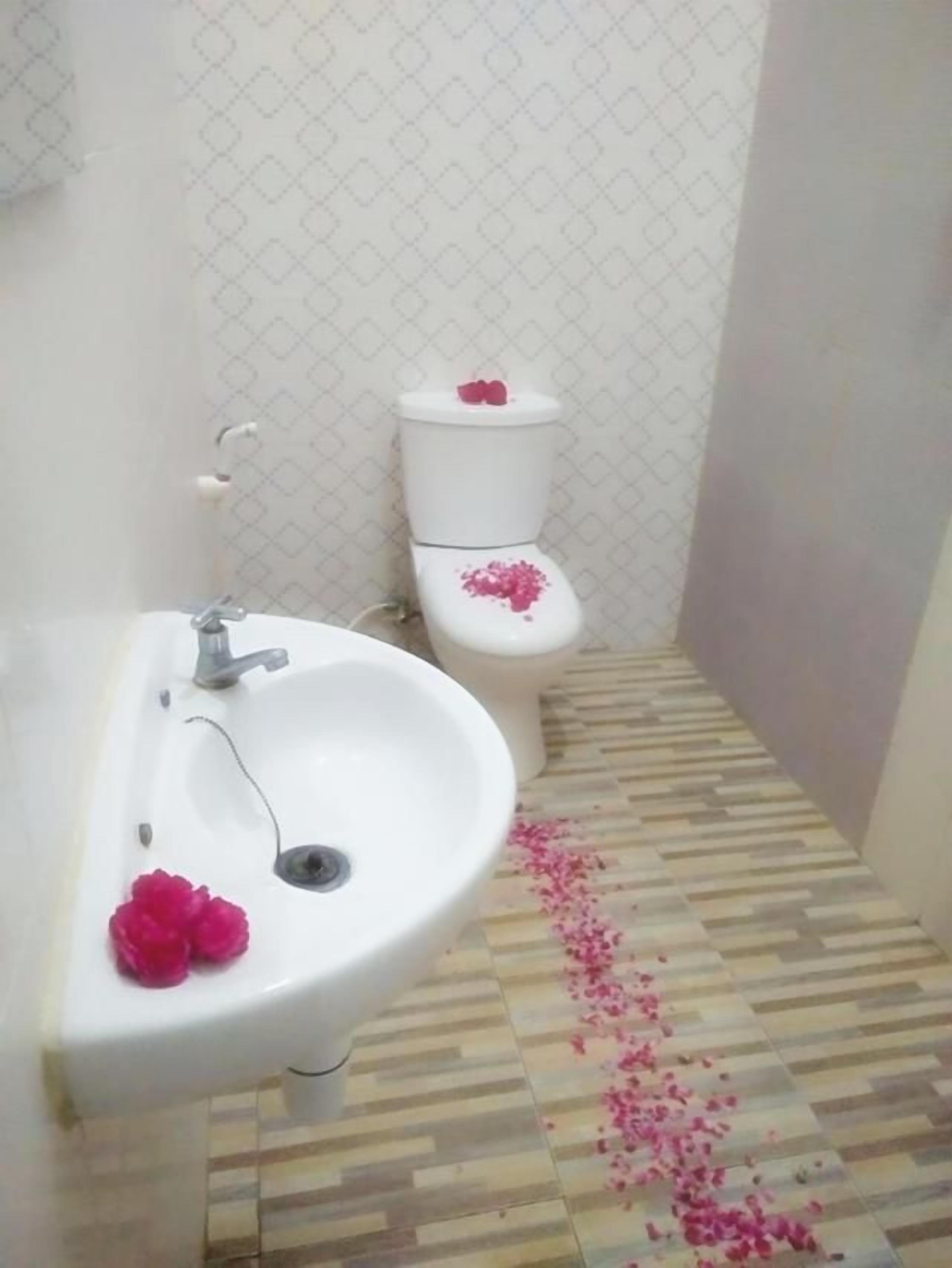 Une salle de bain avec un lavabo blanc, des toilettes et un carrelage décoré.