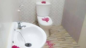 Une salle de bain avec un lavabo blanc, des toilettes et un carrelage décoré.