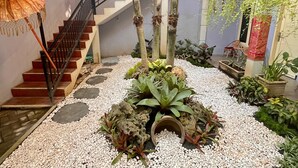 A multi-level indoor garden with a staircase, various plants, and decorative umbrellas. - Clover Homestay (Probolinggo)