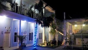A building with a balcony, a staircase, and a well-lit entrance. - Clover Homestay (Probolinggo)