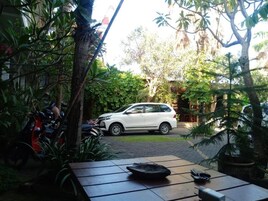 Un coche blanco estacionado en un jardín, con una mesa al frente.