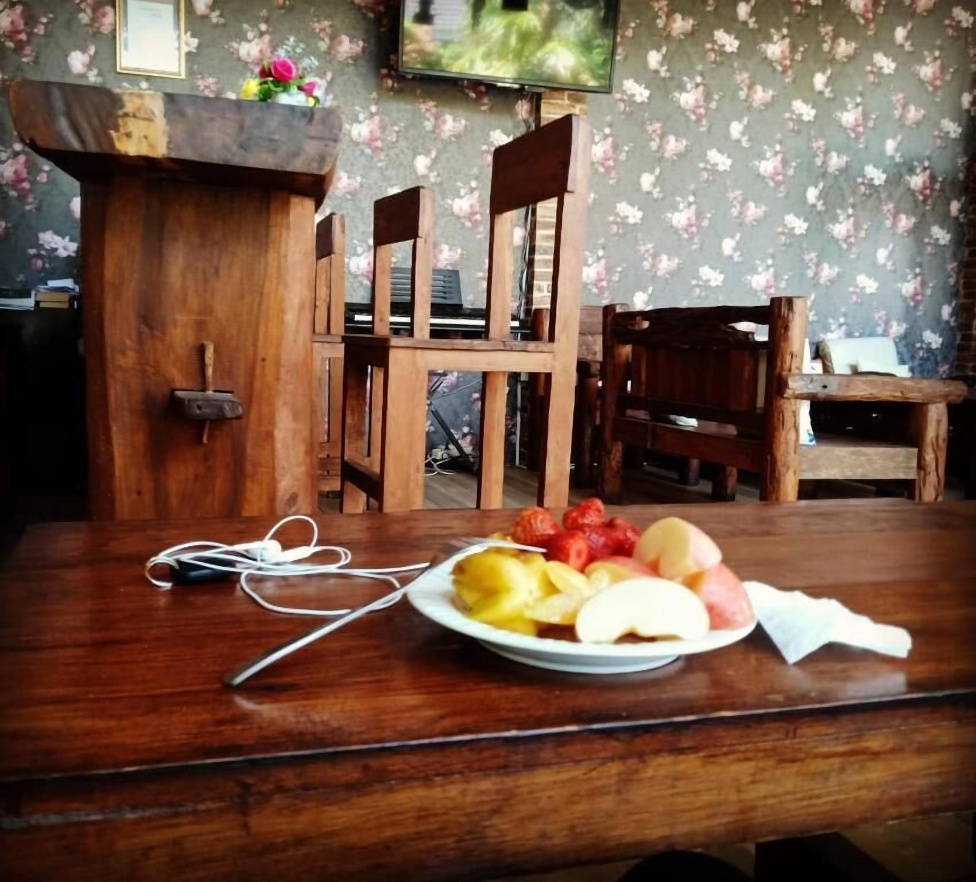 A wooden table with a plate of fruit and a pair of earphones.