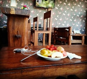 A wooden table with a plate of fruit and a pair of earphones.