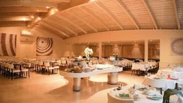 Een ruime balzaal met hoge plafonds en een centrale buffettafel.